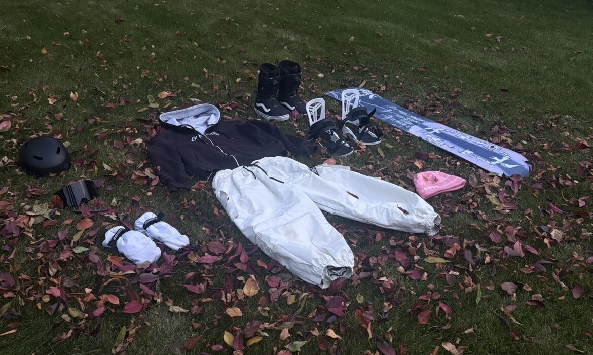 Full 2-1 snowboard kit laid out flat: helmet, goggles, mittens, hoodie, pants, boots, bindings, board and beanie